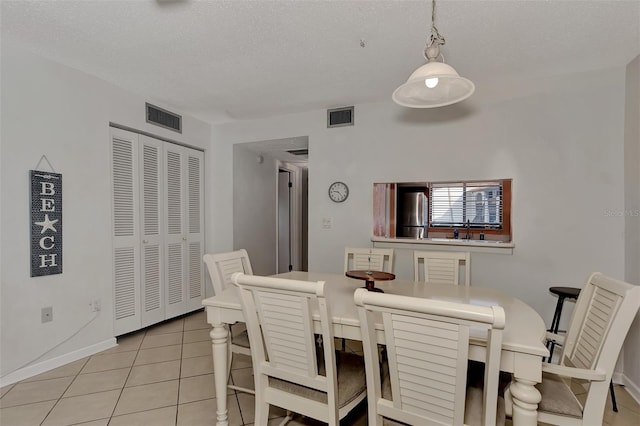 dining room featuring a textured ceiling, sink, and light tile patterned flooring