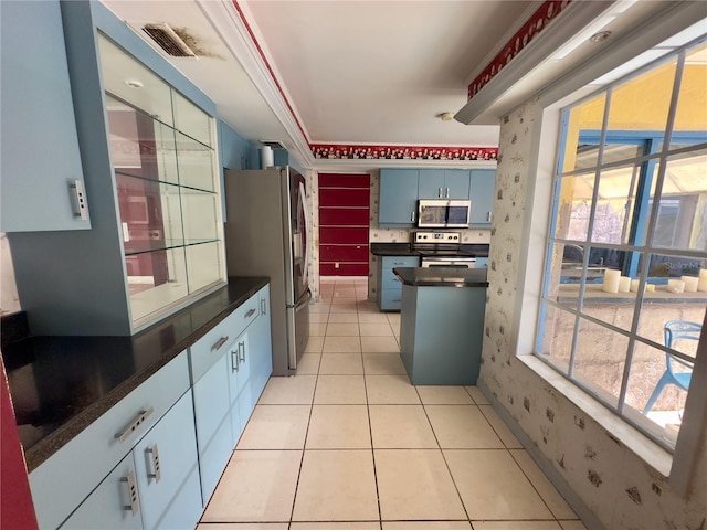 kitchen with crown molding, light tile patterned flooring, stainless steel appliances, and blue cabinetry