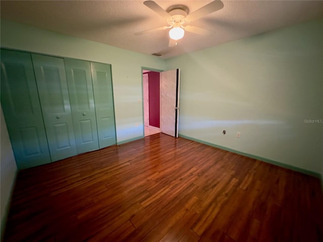 unfurnished bedroom with dark hardwood / wood-style flooring, a closet, and ceiling fan