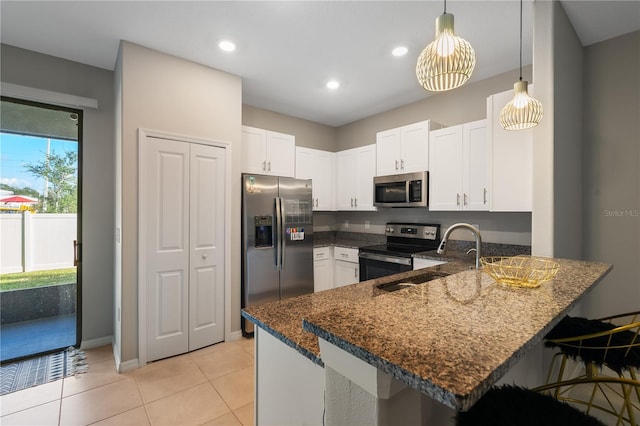 kitchen with kitchen peninsula, appliances with stainless steel finishes, dark stone counters, pendant lighting, and white cabinetry