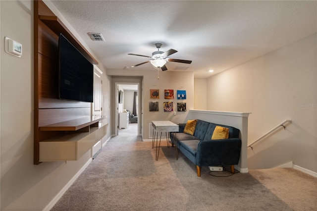 living room with a textured ceiling, light colored carpet, and ceiling fan