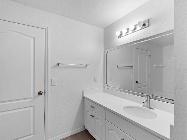 bathroom with vanity, a shower, and a textured ceiling