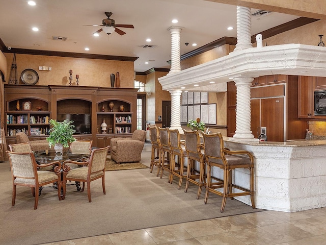 dining room featuring crown molding, ceiling fan, ornate columns, a towering ceiling, and light tile patterned flooring