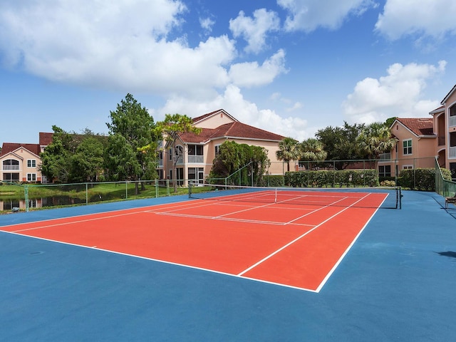 view of tennis court featuring basketball hoop and a water view