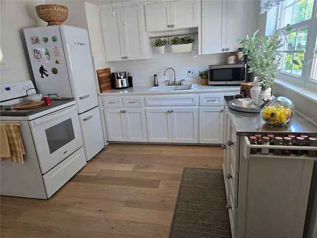 kitchen featuring white cabinetry, sink, light wood-type flooring, and electric stove