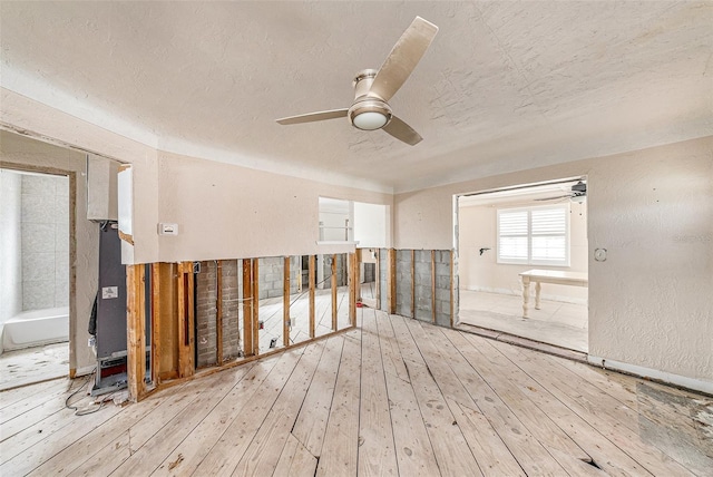 empty room featuring a textured ceiling, light hardwood / wood-style flooring, and ceiling fan