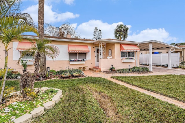 view of front of property with an attached carport, a front yard, fence, driveway, and stucco siding