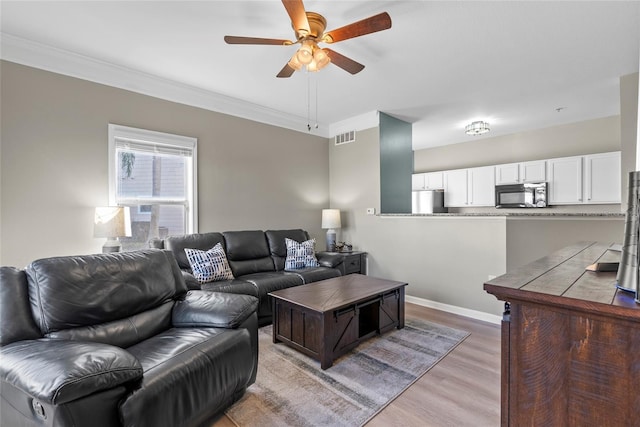 living room with hardwood / wood-style flooring, ceiling fan, and ornamental molding