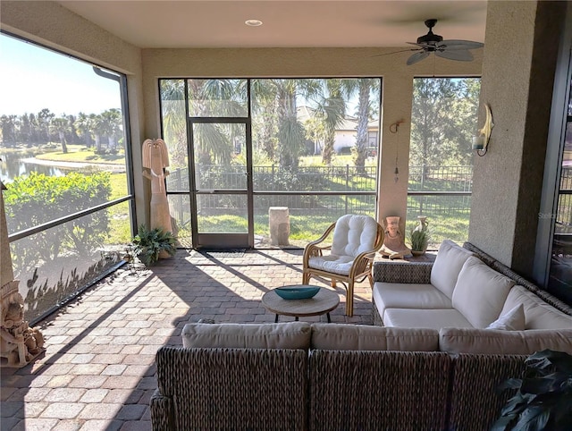 sunroom / solarium with a water view and ceiling fan