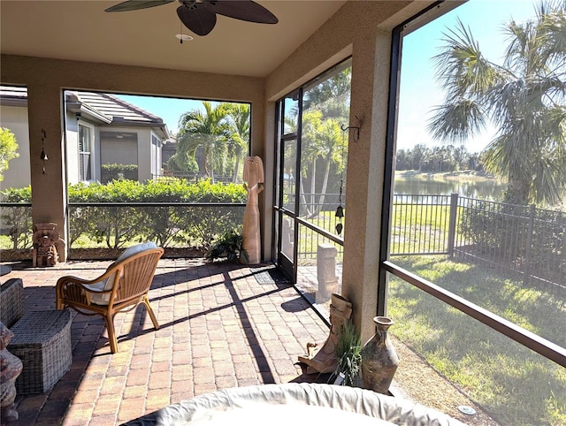 sunroom / solarium featuring ceiling fan and a water view