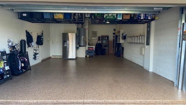 garage featuring stainless steel fridge with ice dispenser and water heater