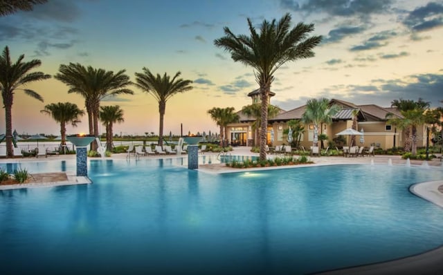 pool at dusk featuring a patio and pool water feature