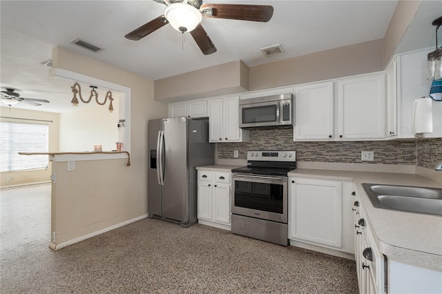 kitchen featuring decorative backsplash, appliances with stainless steel finishes, sink, white cabinets, and hanging light fixtures