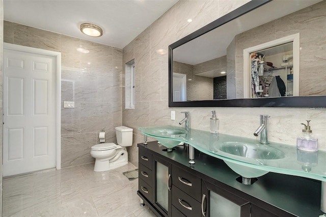 bathroom with vanity, tile walls, and toilet