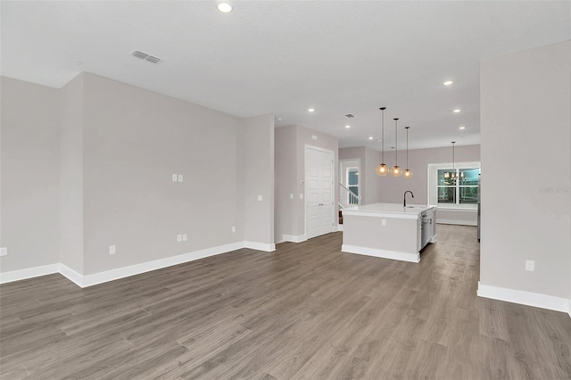 unfurnished living room with an inviting chandelier, light hardwood / wood-style flooring, and sink