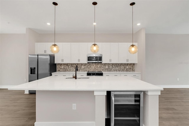 kitchen with appliances with stainless steel finishes, an island with sink, sink, and wine cooler