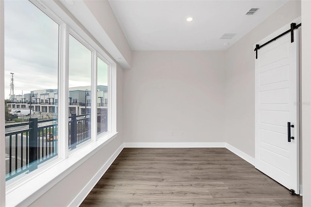 spare room with a barn door and hardwood / wood-style floors