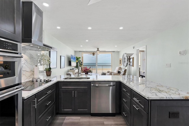 kitchen with kitchen peninsula, stainless steel appliances, and wall chimney range hood