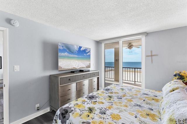 bedroom featuring a textured ceiling, access to exterior, expansive windows, and dark hardwood / wood-style floors