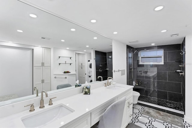 bathroom with vanity, a tile shower, and stacked washing maching and dryer