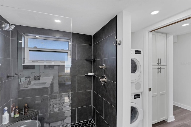 bathroom featuring tiled shower, wood-type flooring, and stacked washer / dryer