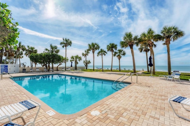 view of swimming pool featuring a patio and a water view