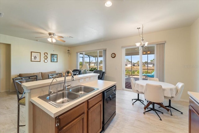 kitchen featuring hanging light fixtures, a kitchen island with sink, ceiling fan with notable chandelier, black dishwasher, and sink