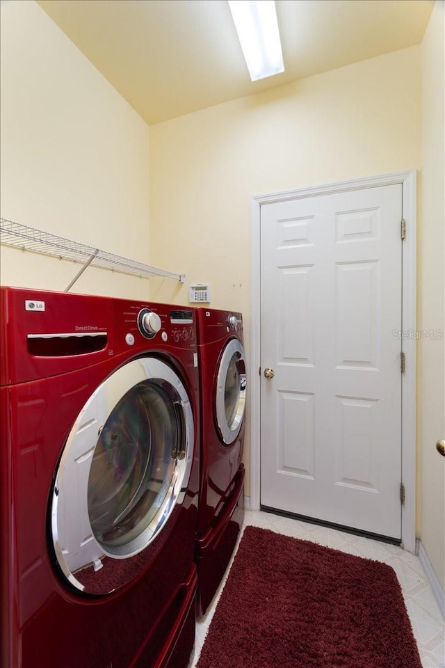 clothes washing area with washer and dryer and light tile patterned floors