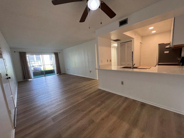 unfurnished living room featuring ceiling fan, dark hardwood / wood-style flooring, and sink