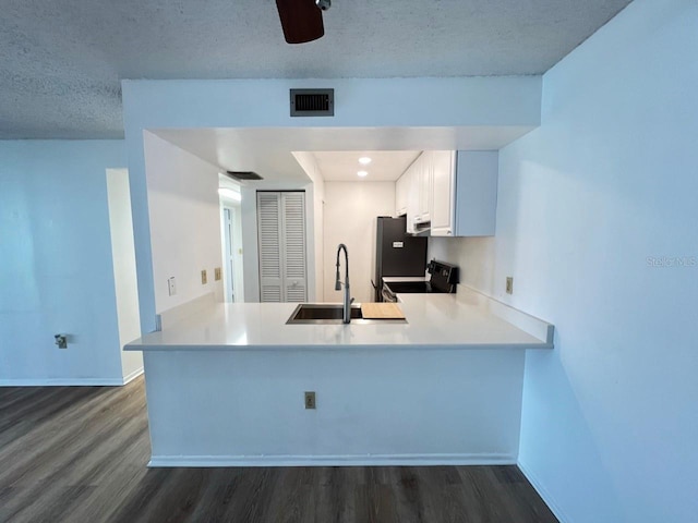 kitchen with kitchen peninsula, sink, white cabinets, and a textured ceiling