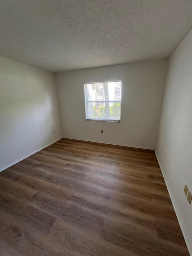 empty room featuring a textured ceiling and dark wood-type flooring