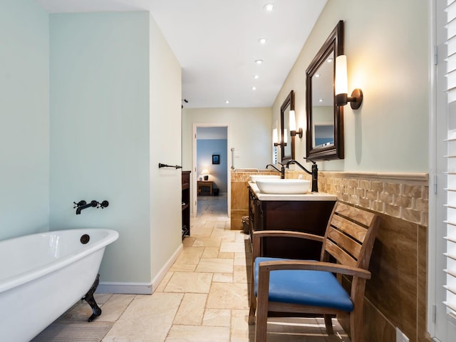 bathroom featuring a washtub, tile walls, and vanity