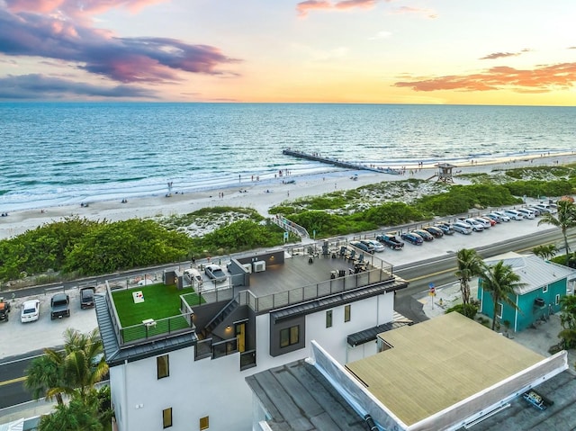 aerial view at dusk with a water view and a view of the beach