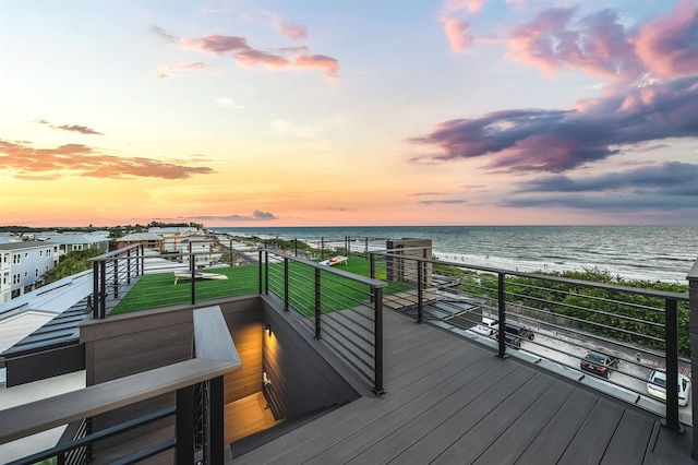 deck at dusk featuring a water view and a view of the beach