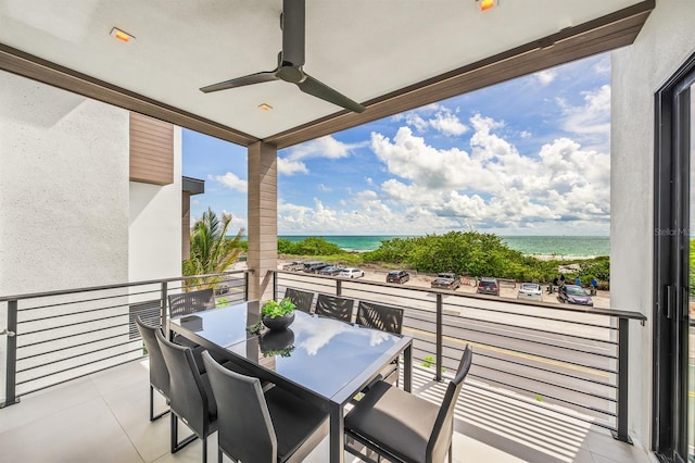 balcony with a view of the beach, a water view, and ceiling fan