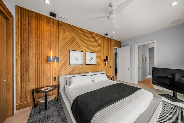 bedroom featuring ceiling fan, light carpet, and wooden walls