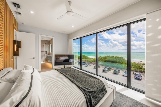 bedroom featuring a view of the beach, a water view, ceiling fan, access to exterior, and connected bathroom