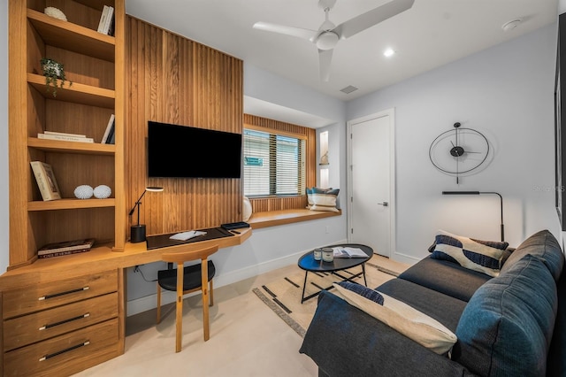 living room featuring ceiling fan and built in desk