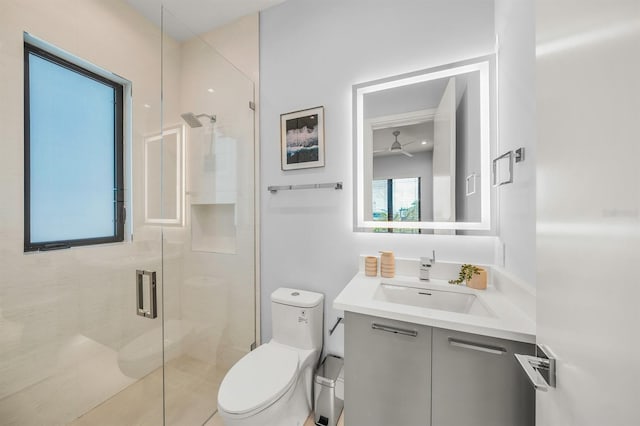 bathroom featuring vanity, toilet, ceiling fan, and a shower with shower door