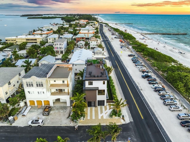 aerial view at dusk featuring a water view and a view of the beach