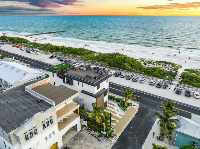 aerial view at dusk with a water view and a beach view