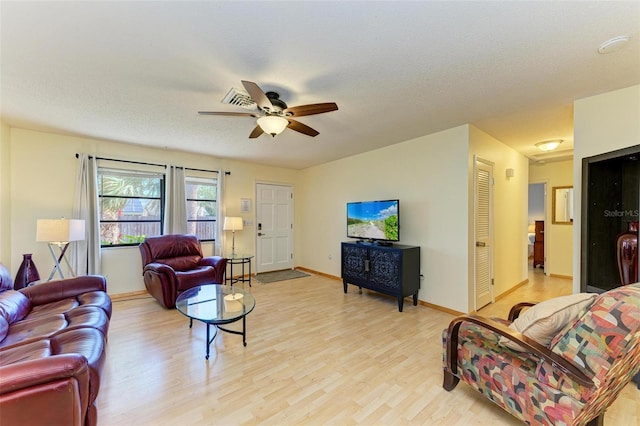 living room featuring ceiling fan, a textured ceiling, and light wood-type flooring