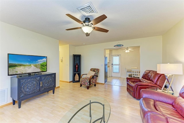 living room featuring ceiling fan, a textured ceiling, and light wood-type flooring