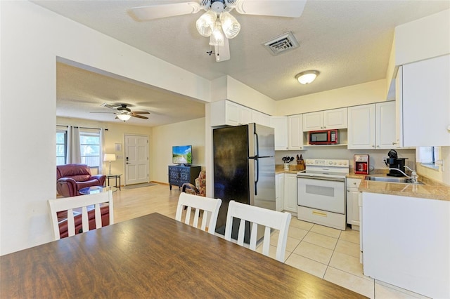 kitchen with stainless steel refrigerator, white cabinetry, sink, and white electric range oven