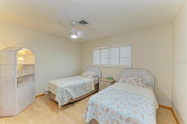 bedroom with a textured ceiling, light hardwood / wood-style floors, and ceiling fan