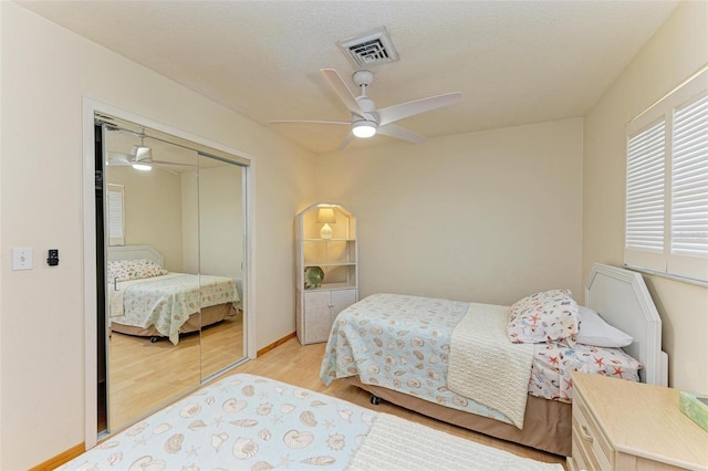 bedroom featuring a textured ceiling, light hardwood / wood-style flooring, a closet, and ceiling fan