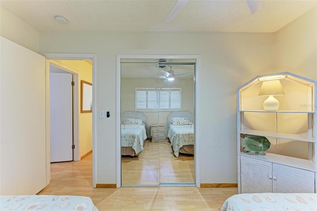 bedroom with ceiling fan, light hardwood / wood-style floors, a textured ceiling, and a closet