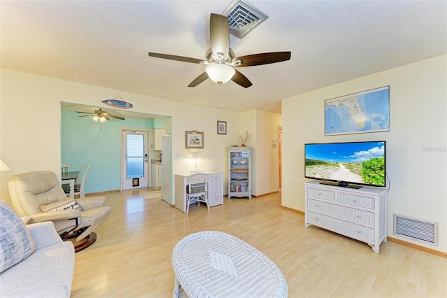 living room with hardwood / wood-style flooring, ceiling fan, and a textured ceiling