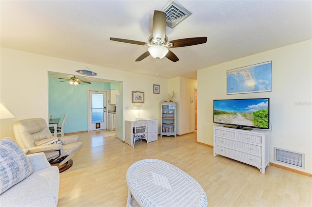 living room with a textured ceiling, light hardwood / wood-style floors, and ceiling fan