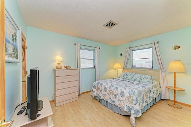 bedroom with multiple windows, wood-type flooring, and a textured ceiling